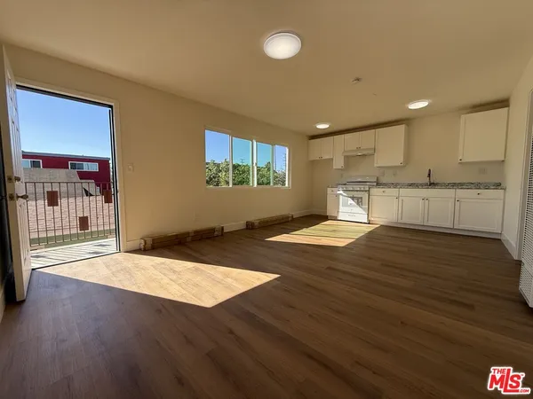 a view of a kitchen with kitchen island a sink wooden floor and a refrigerator