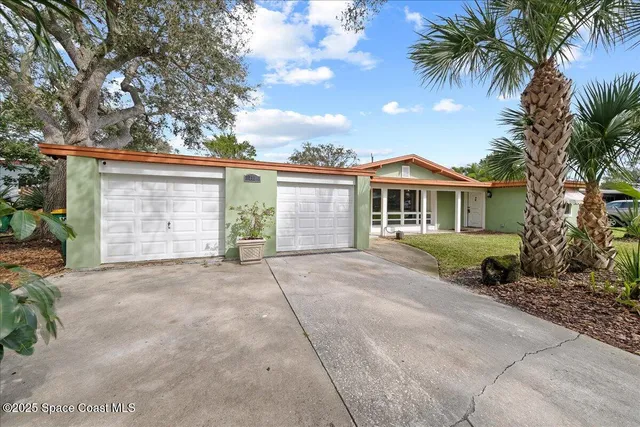 front view of a house with a yard and palm trees