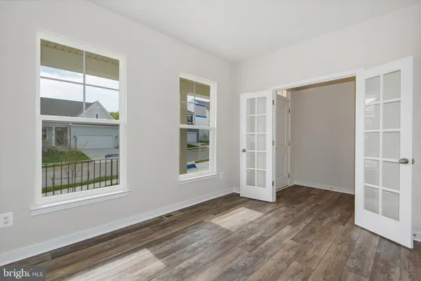 an empty room with wooden floor and windows