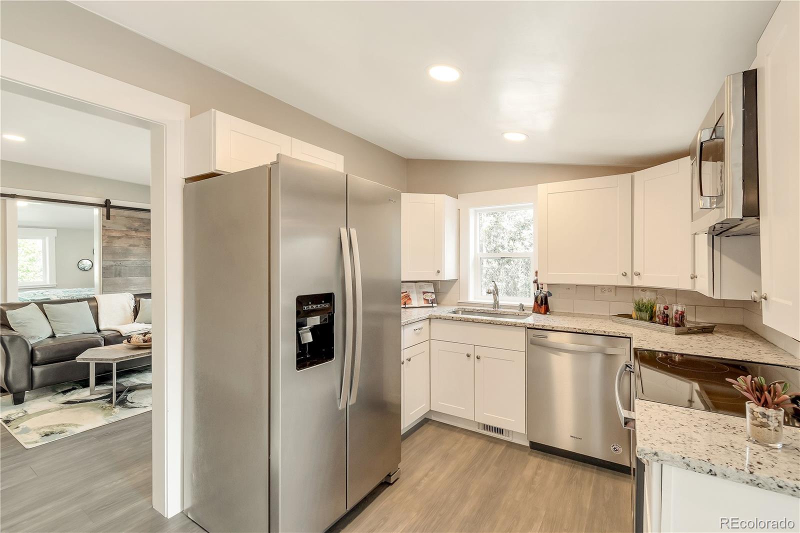 2868 Benton Street Wheat Ridge, CO 80214 - Photo 4 of 22 a kitchen with stainless steel appliances granite countertop a refrigerator a sink dishwasher a stove and white cabinets with wooden floor
