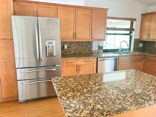 a kitchen with granite countertop a refrigerator and a stove top oven
