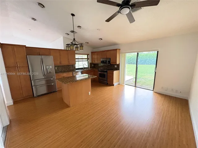 a view of a kitchen with furniture a ceiling fan and wooden floor