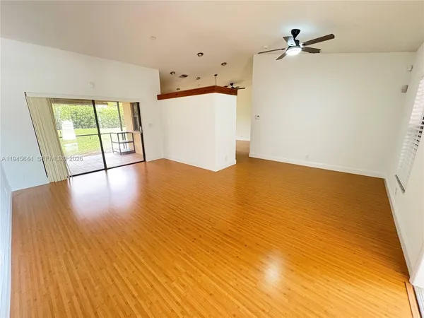 a view of empty room with wooden floor and fan