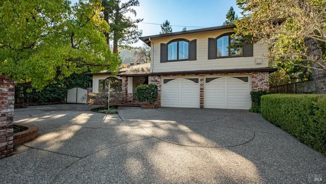 a view of a white house with a large tree