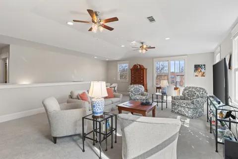 a living room with furniture a ceiling fan and a flat screen tv