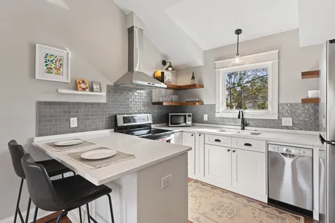 a kitchen with stainless steel appliances a table chairs and a refrigerator