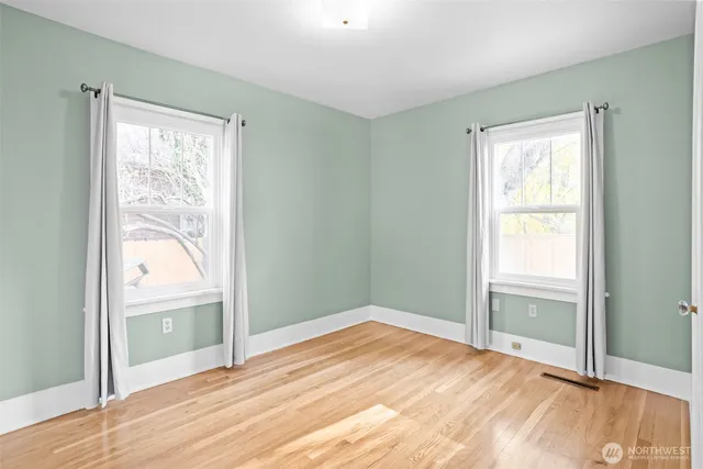 a view of empty room with window and wooden floor