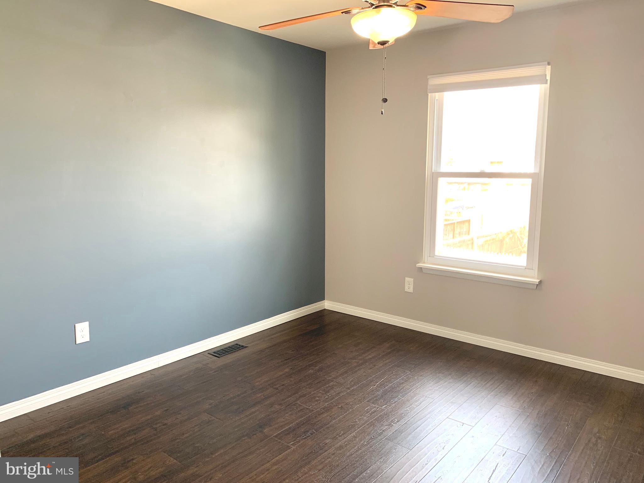 808 207th Street Pasadena, MD 21122 - Photo 11 of 20 an empty room with wooden floor and windows