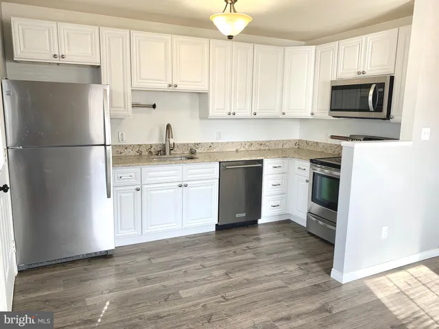 a kitchen with stainless steel appliances granite countertop wooden cabinets a stove a sink and a microwave