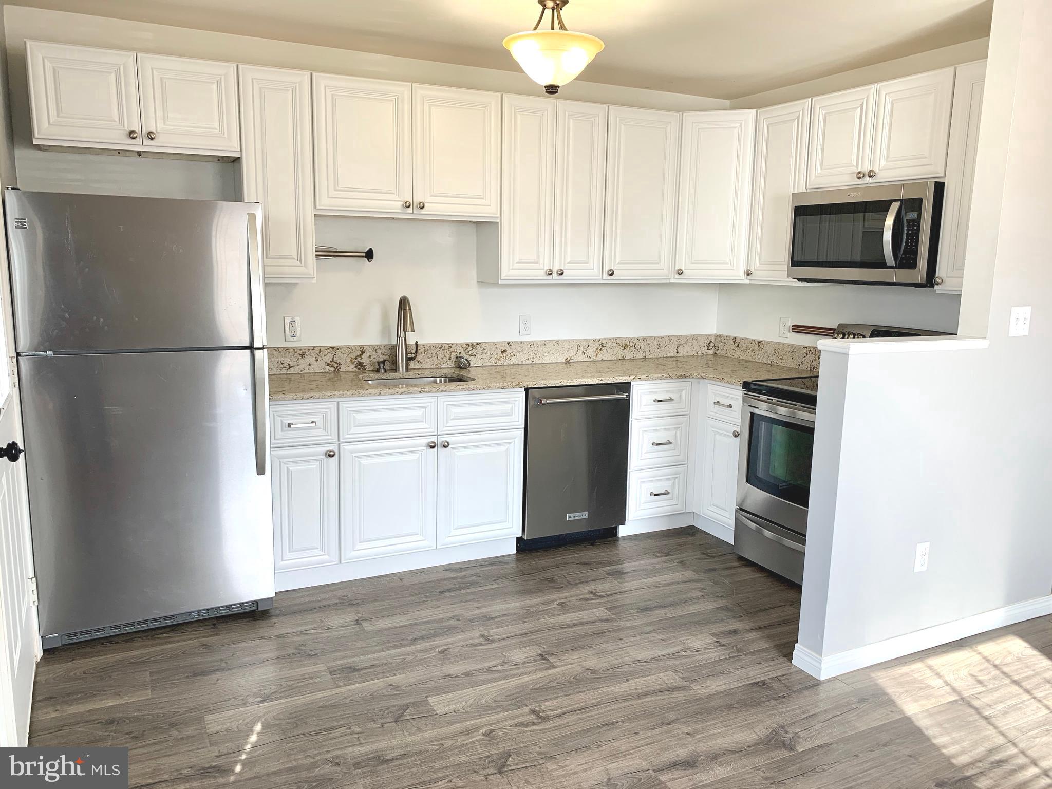 808 207th Street Pasadena, MD 21122 - Photo 4 of 20 a kitchen with stainless steel appliances granite countertop wooden cabinets a stove a sink and a microwave
