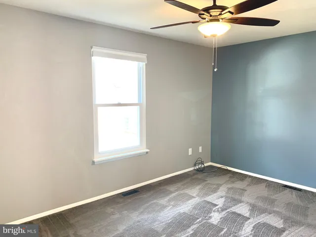 an empty room with a window and a fan
