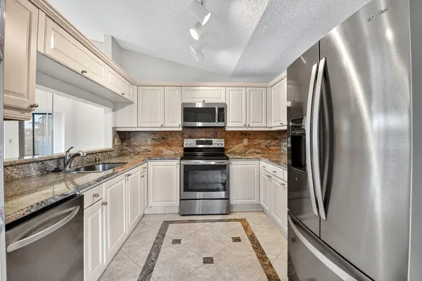 a kitchen with stainless steel appliances granite countertop a refrigerator and a sink