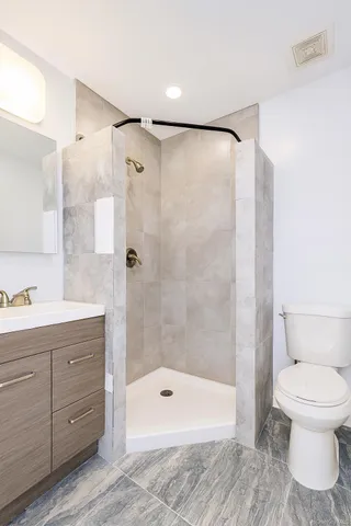 a bathroom with a shower sink vanity mirror and toilet