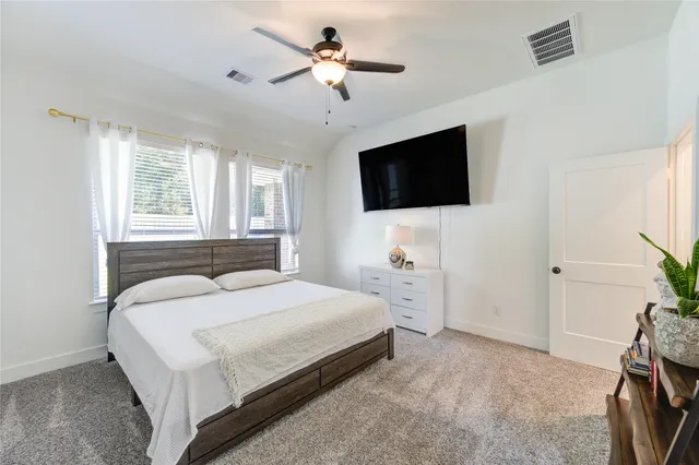 a bedroom with a bed a flat screen tv and a window