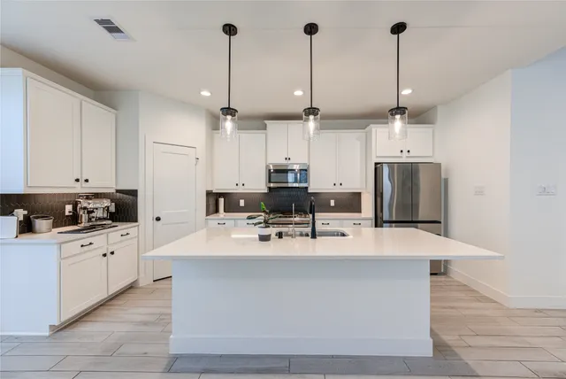 a large kitchen with stainless steel appliances kitchen island granite countertop a sink a stove and refrigerator