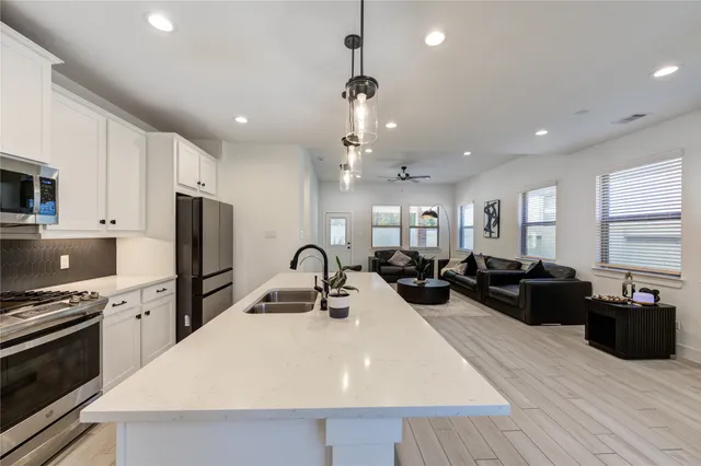 a large kitchen with sink a refrigerator and chairs