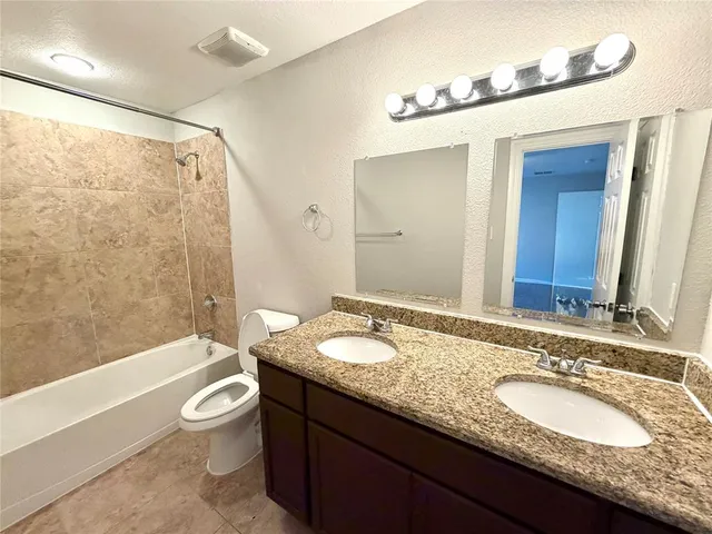 a bathroom with a granite countertop tub sink and mirror