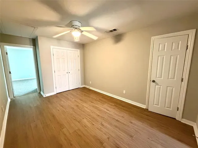 an empty room with wooden floor and fan