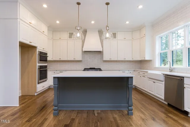 a large kitchen with granite countertop a stove a sink dishwasher a kitchen island with wooden floor and cabinets