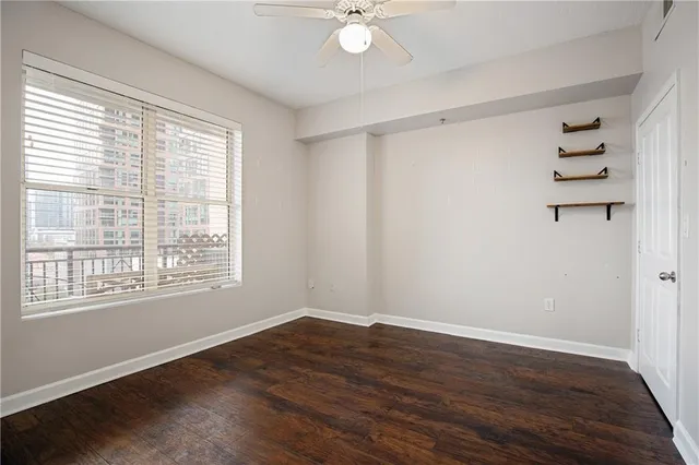 an empty room with wooden floor fan and windows
