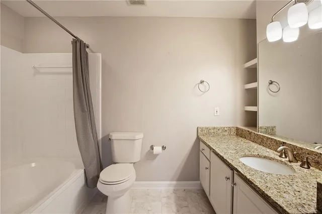 a bathroom with a granite countertop sink toilet and shower