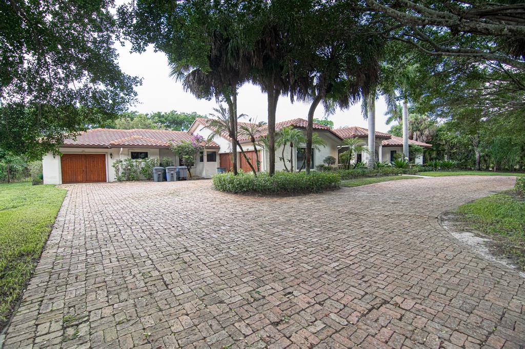 8208 Twin Lake Drive Boca Raton, FL 33496 - Photo 2 of 53 a front view of a house with a garden and trees