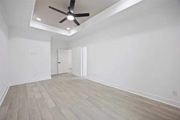 an empty room with wooden floor and ceiling fan