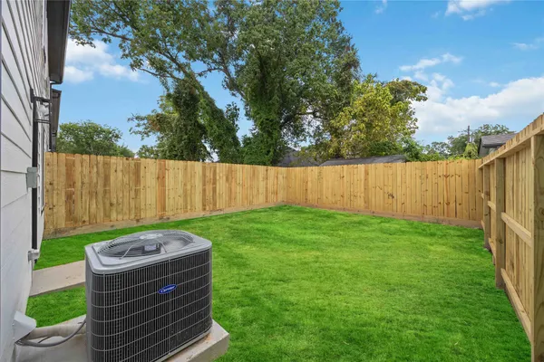 a view of a backyard with a large tree and wooden fence