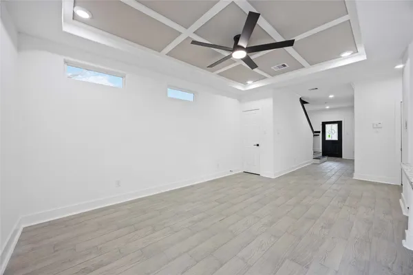 an empty room with wooden floor ceiling fan and windows