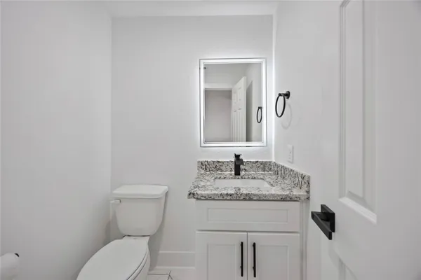 a bathroom with a granite countertop toilet sink and mirror
