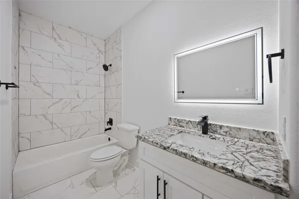 a bathroom with a granite countertop sink a toilet and bathtub