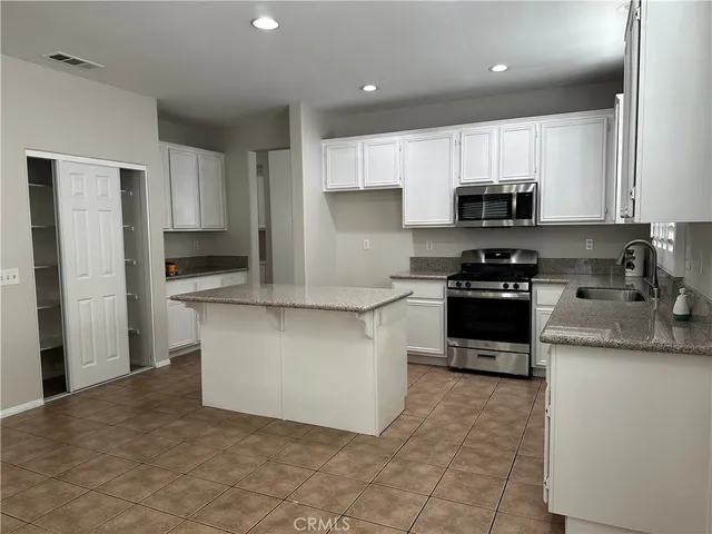 a kitchen with stainless steel appliances a sink a stove a microwave a sink a refrigerator and cabinets