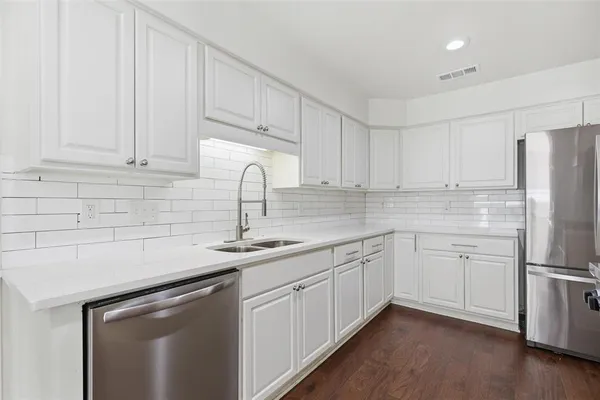 a kitchen with white cabinets sink and refrigerator