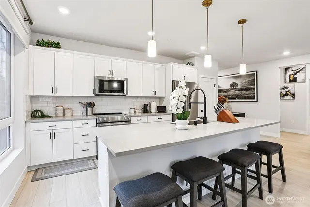 a kitchen with stainless steel appliances granite countertop a sink a stove a microwave a island with a dining table and chairs