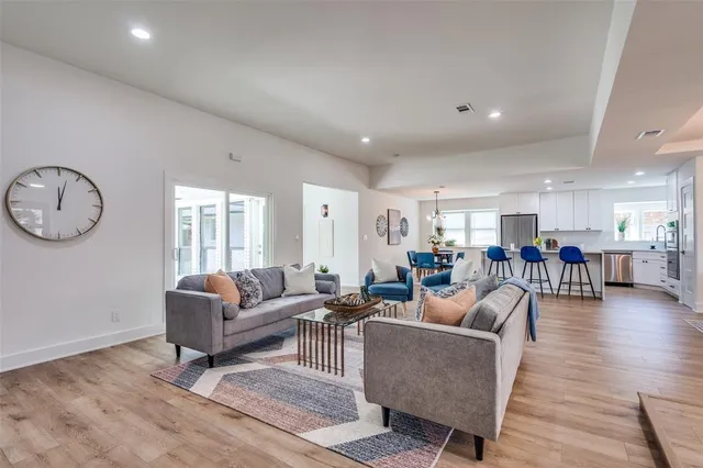 a living room with furniture kitchen view and a wooden floor