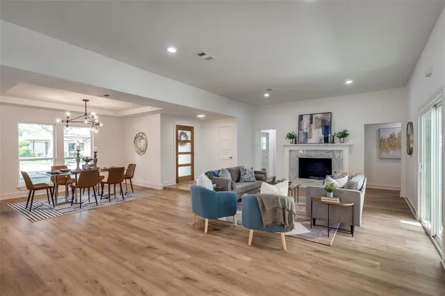 a living room with furniture a fireplace and a dining table with wooden floor