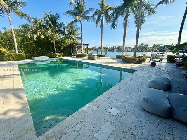 a view of swimming pool with a lawn chairs and palm trees