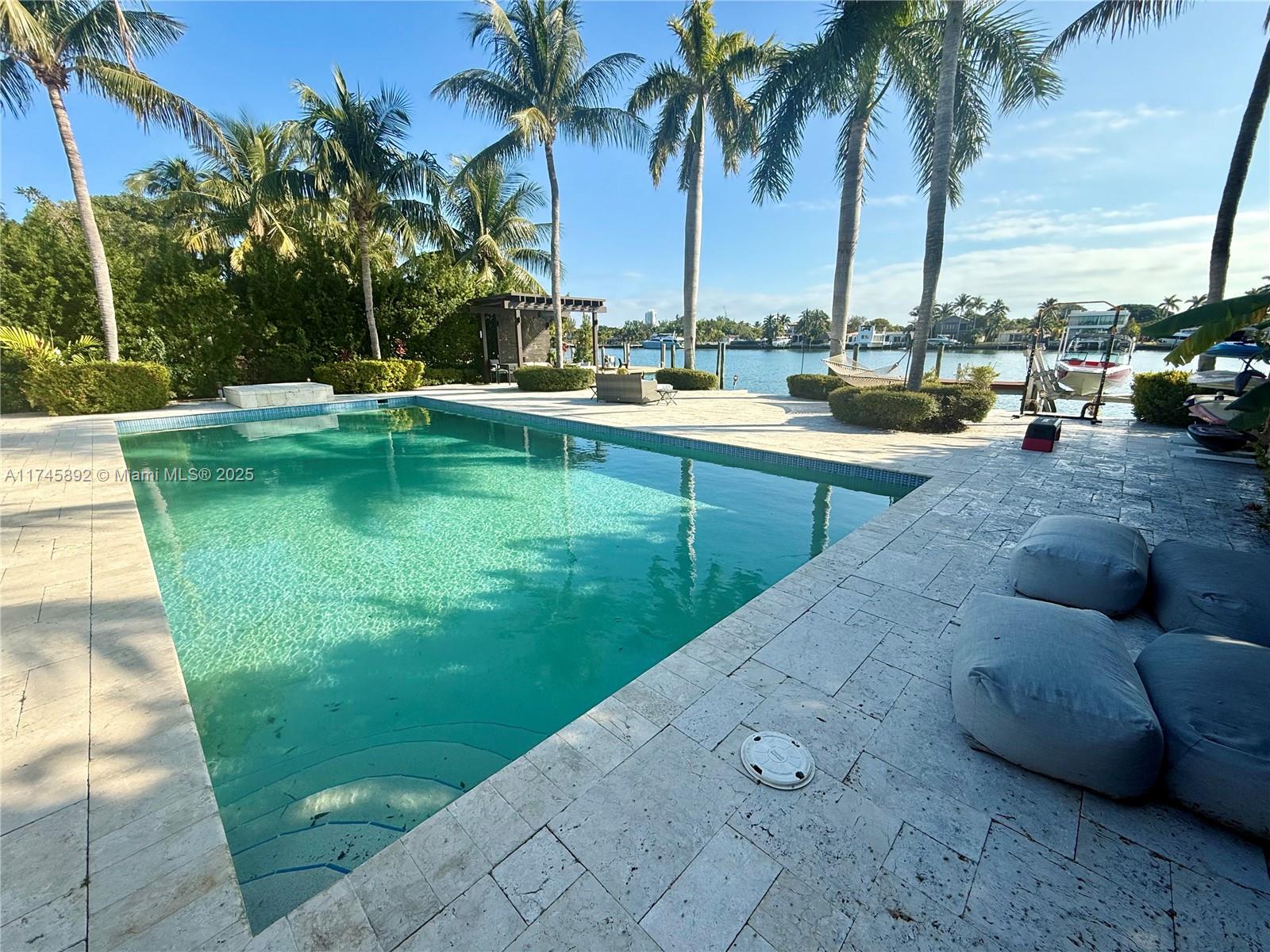 1670 Daytonia Road Miami Beach, FL 33141 - Photo 9 of 24 a view of swimming pool with a lawn chairs and palm trees