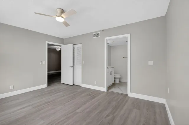 an empty room with wooden floor and a ceiling fan