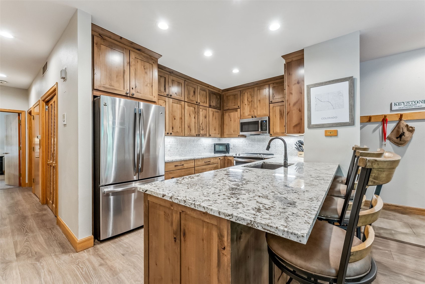 1203 West Keystone Road, Unit 2711 Keystone, CO 80435 - Photo 9 of 36 Kitchen featuring light hardwood / wood-style floors, appliances with stainless steel finishes, kitchen peninsula, and backsplash