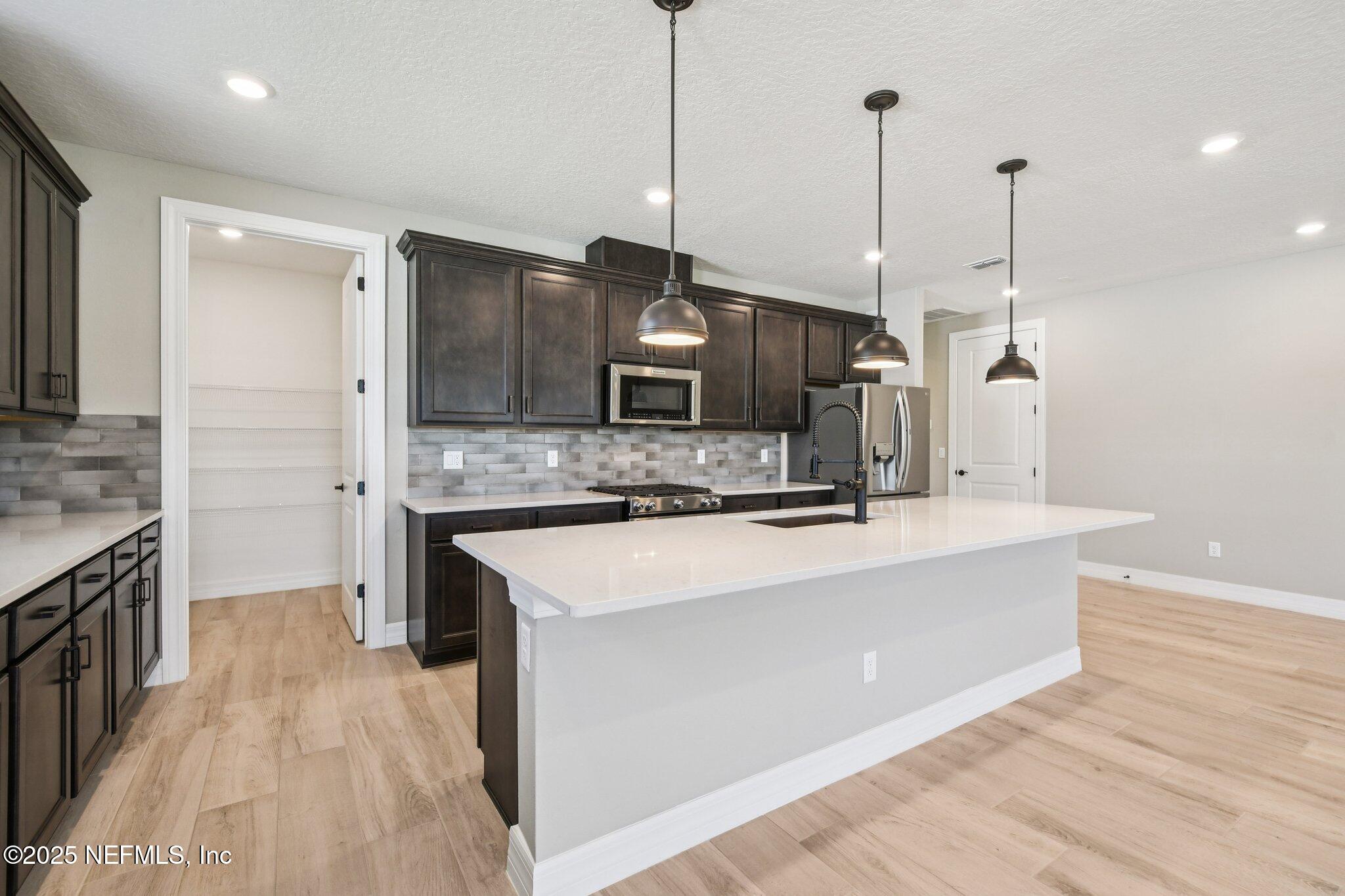 729 Continuum Loop Yulee, FL 32097 - Photo 11 of 31 a large kitchen with granite countertop a sink a counter top space stainless steel appliances and cabinets