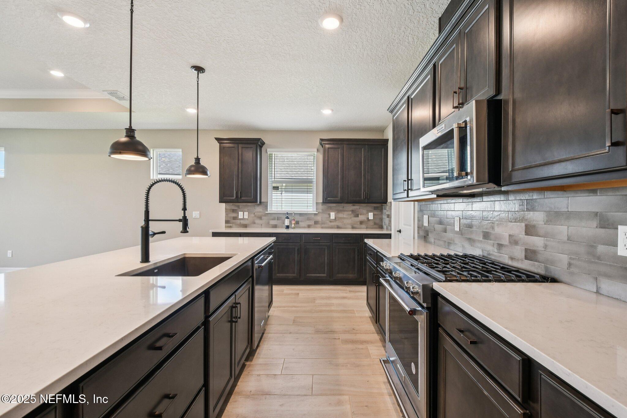 729 Continuum Loop Yulee, FL 32097 - Photo 10 of 31 a kitchen with kitchen island granite countertop a sink stainless steel appliances and cabinets