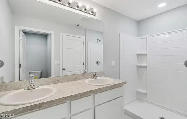 a bathroom with a granite countertop sink a toilet and a mirror