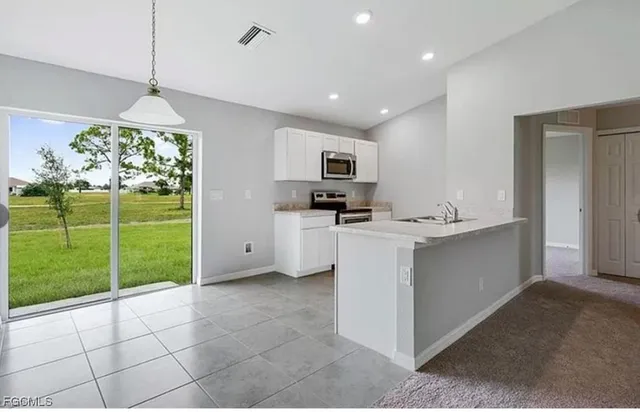 a kitchen with kitchen island a sink stainless steel appliances and a counter top space
