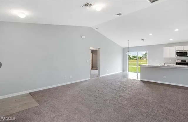a view of an empty room and a kitchen