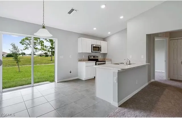 a kitchen with kitchen island a sink stainless steel appliances and a chandelier