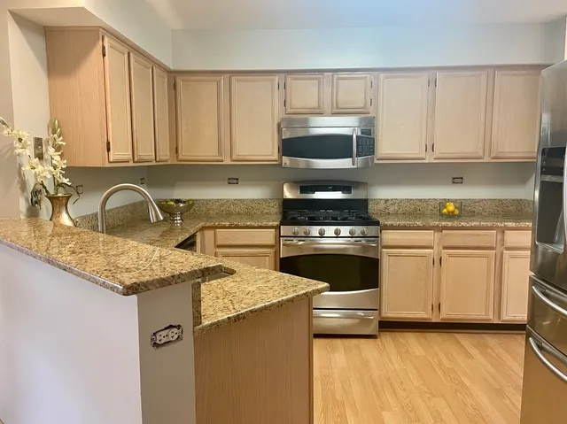 a kitchen with granite countertop a sink a stove top oven and cabinetry