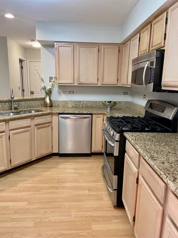 a kitchen with stainless steel appliances granite countertop a stove a sink and a microwave