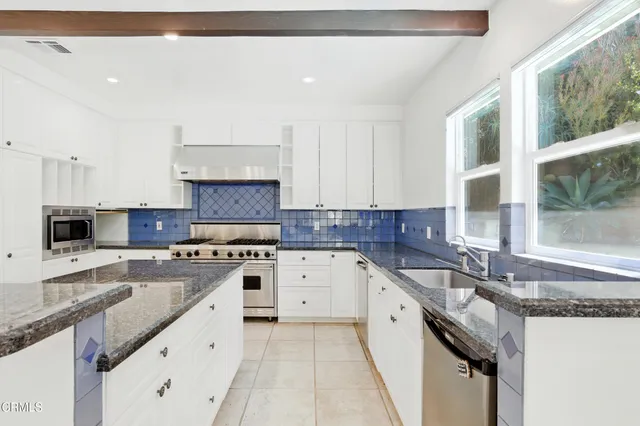 a kitchen with granite countertop a sink stove and cabinets