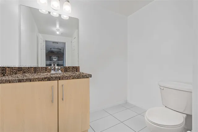 a bathroom with a granite countertop sink a toilet and a mirror